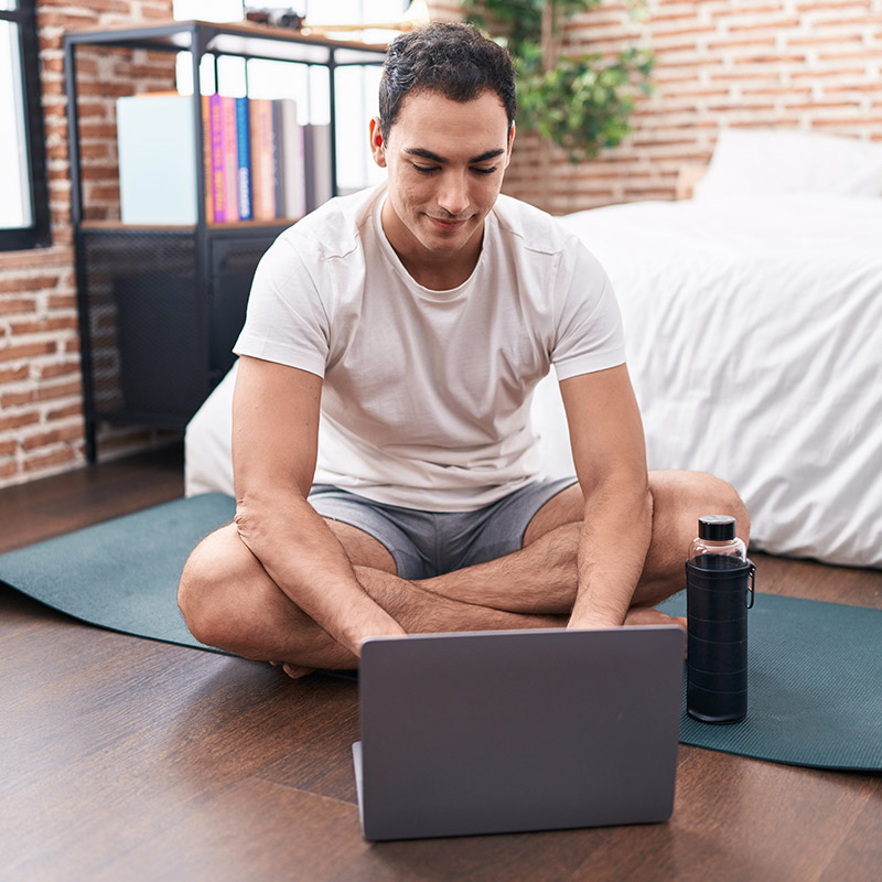 Young male sitting on yoga mat looking at his NutriKane Affiliate Program dashboard